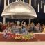 Performers arrayed around a table